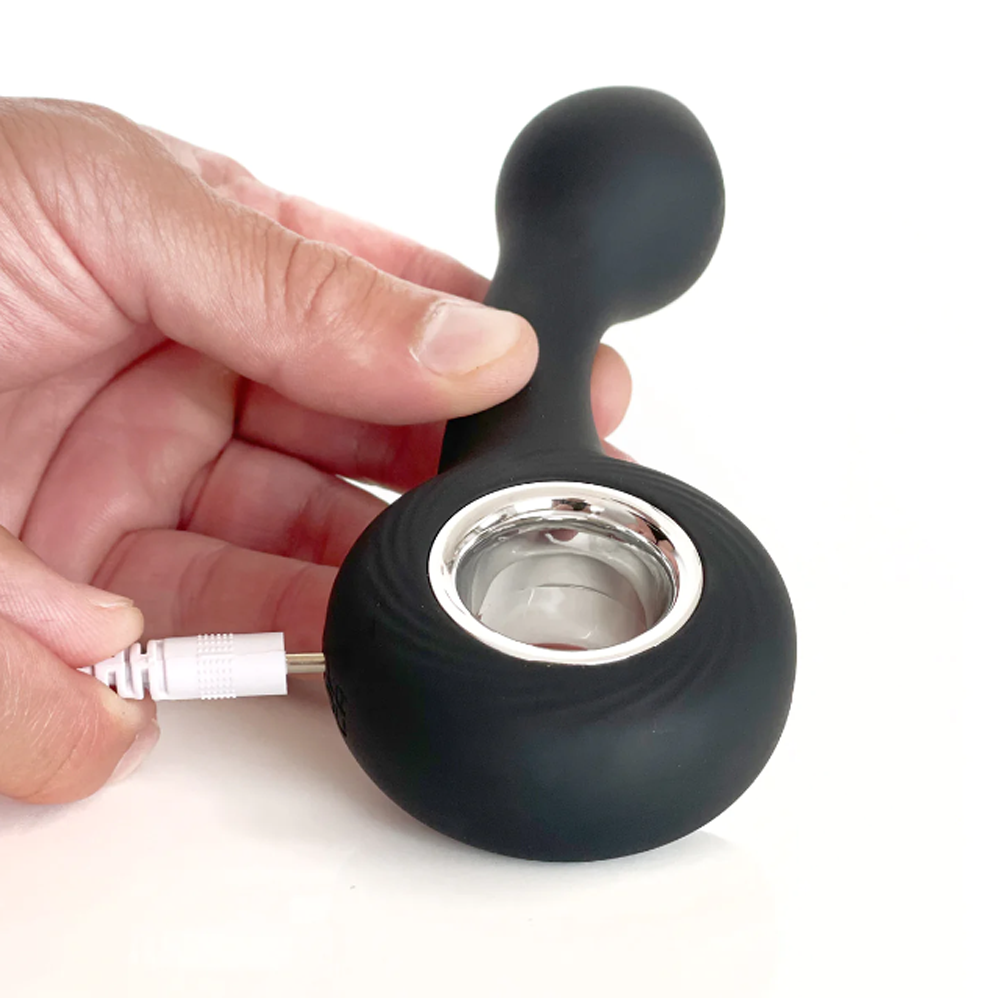 A black G-spot vibrator with a charging cable being inserted.