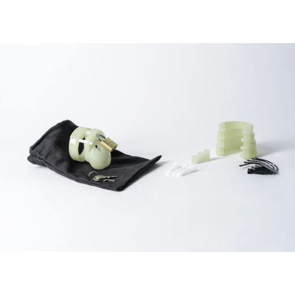 Glow-in-the-dark chastity cage kit with lock, keys, and accessories.