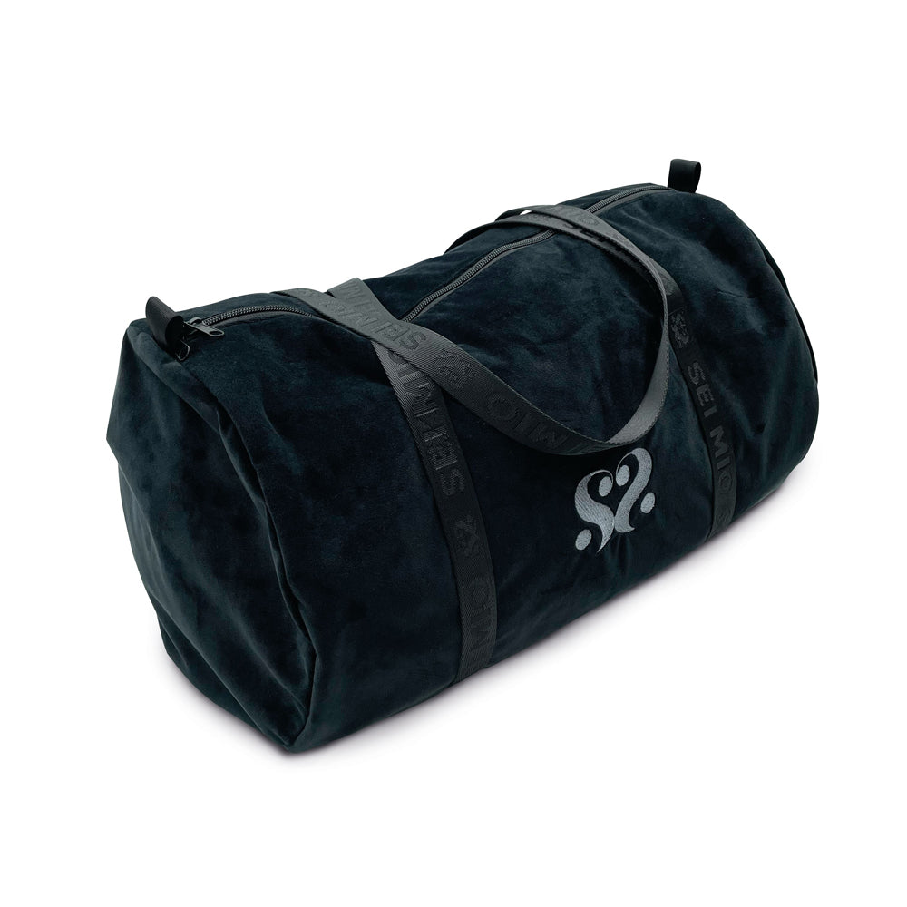 A dark velvet duffle bag with grey straps and a white logo.