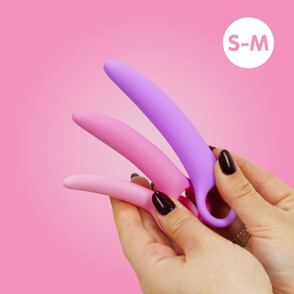 Curved silicone dilator set in pink and purple held by hands.