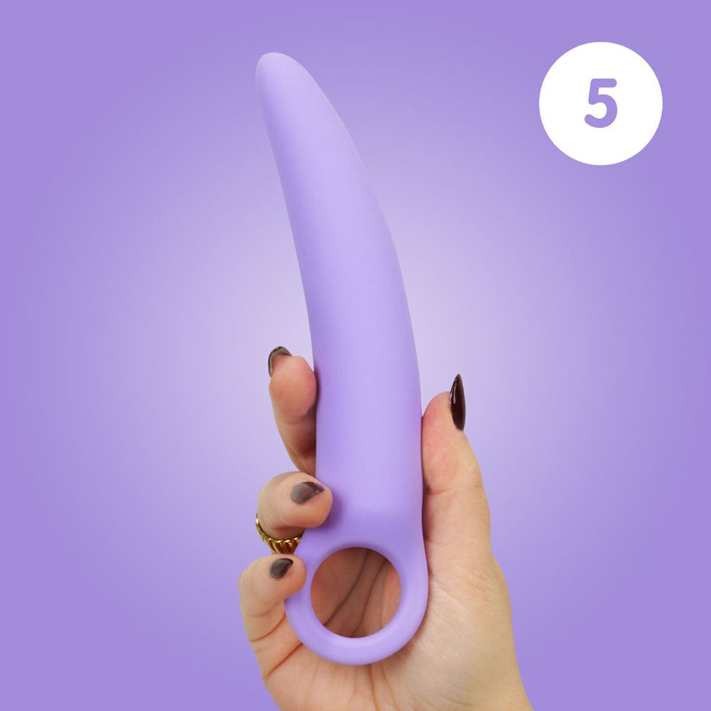 A hand holds a curved purple silicone dilator with a finger loop.