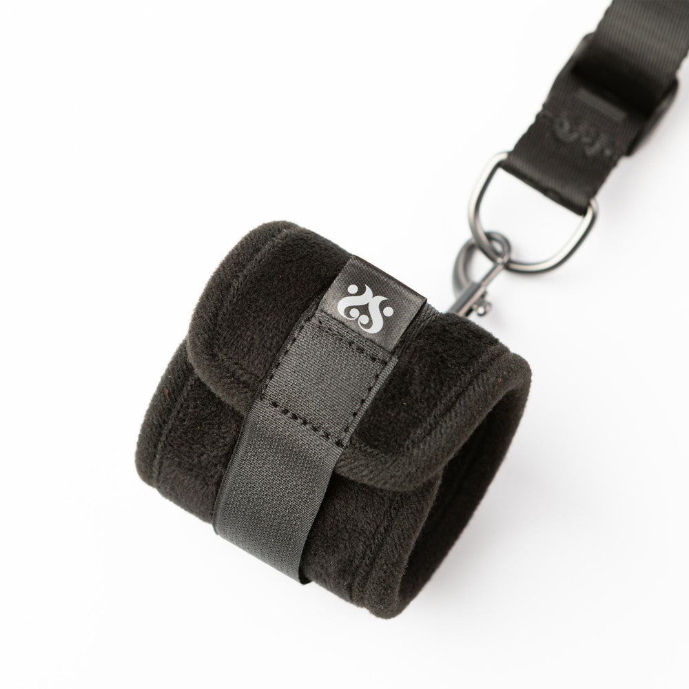 Black padded cuff with a strap and metal clip attached to a black strap.