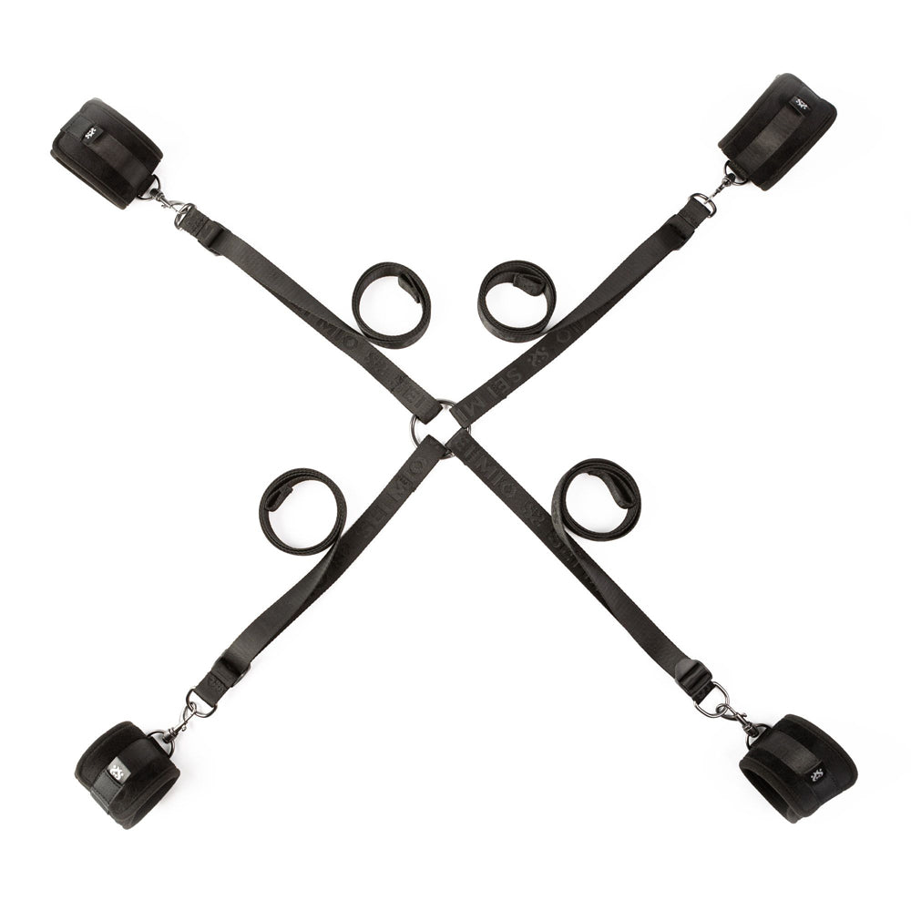 Black adjustable bed restraint system with four padded cuffs and a central ring.