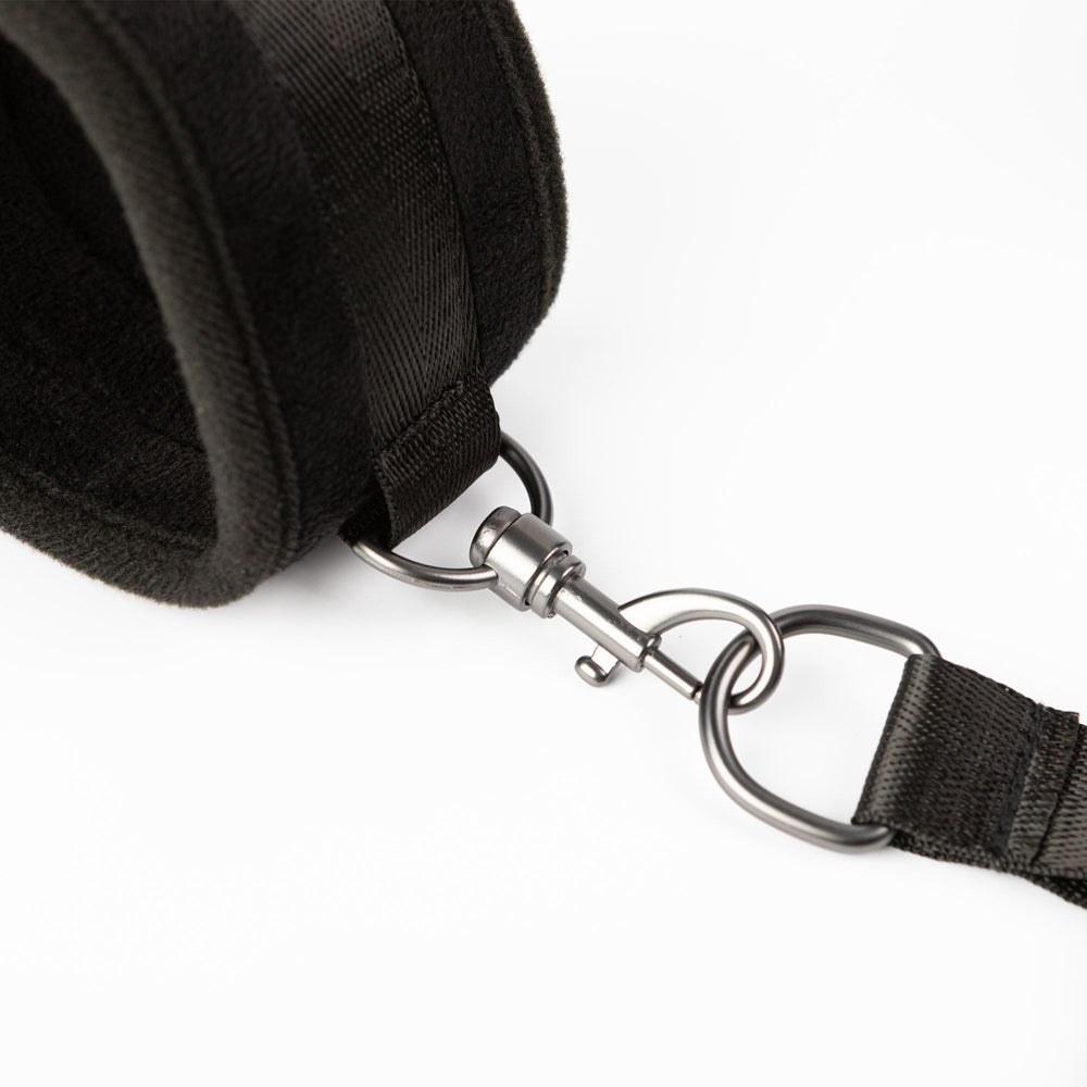 Black velvet padded restraint cuffs with metal clasp and strap.