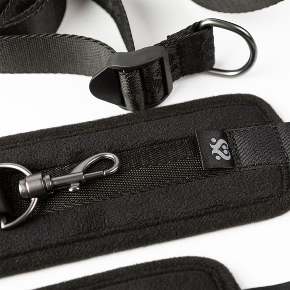 Black padded restraint system with metal clip and D-ring.