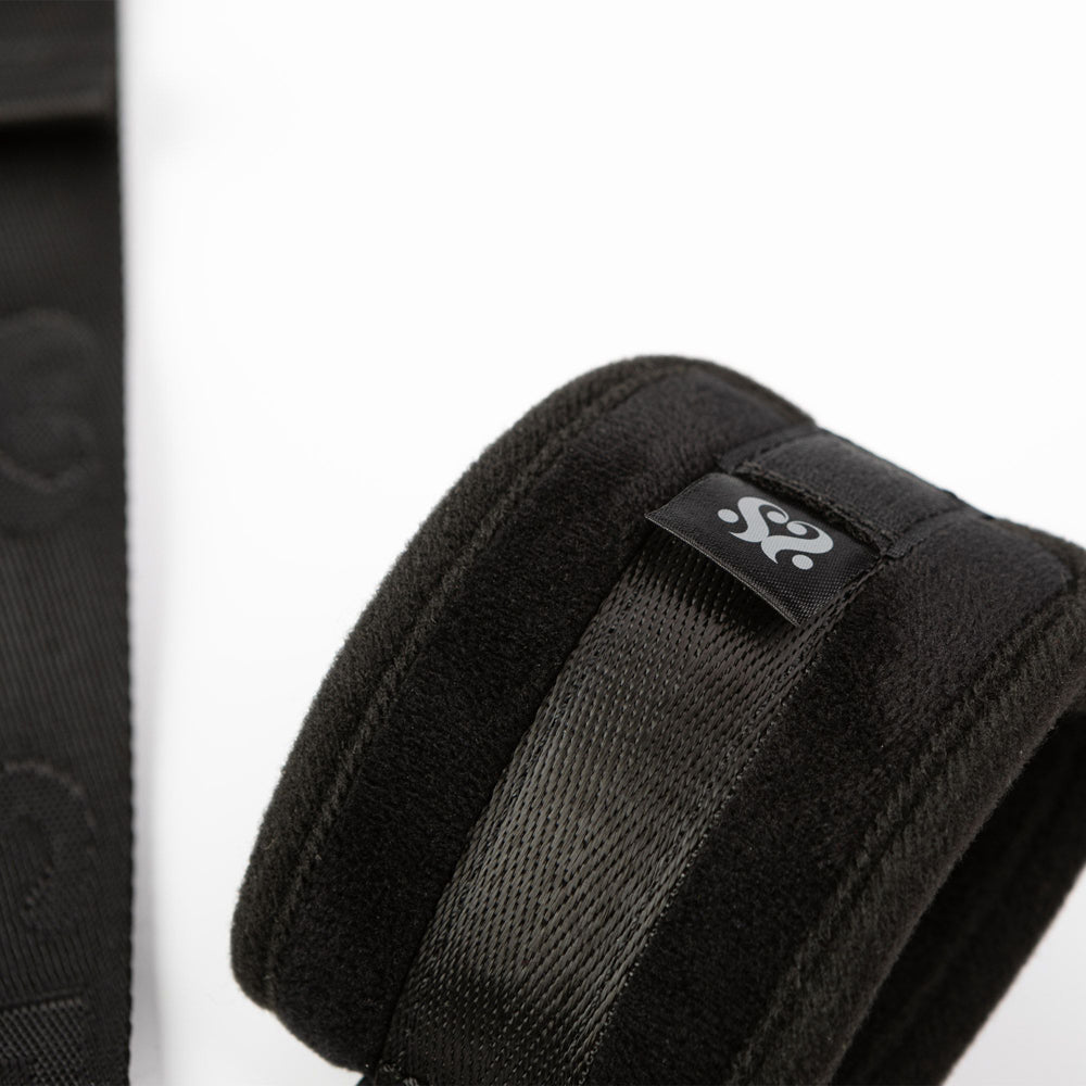 Black padded wrist cuff with a woven strap and a logo tag.