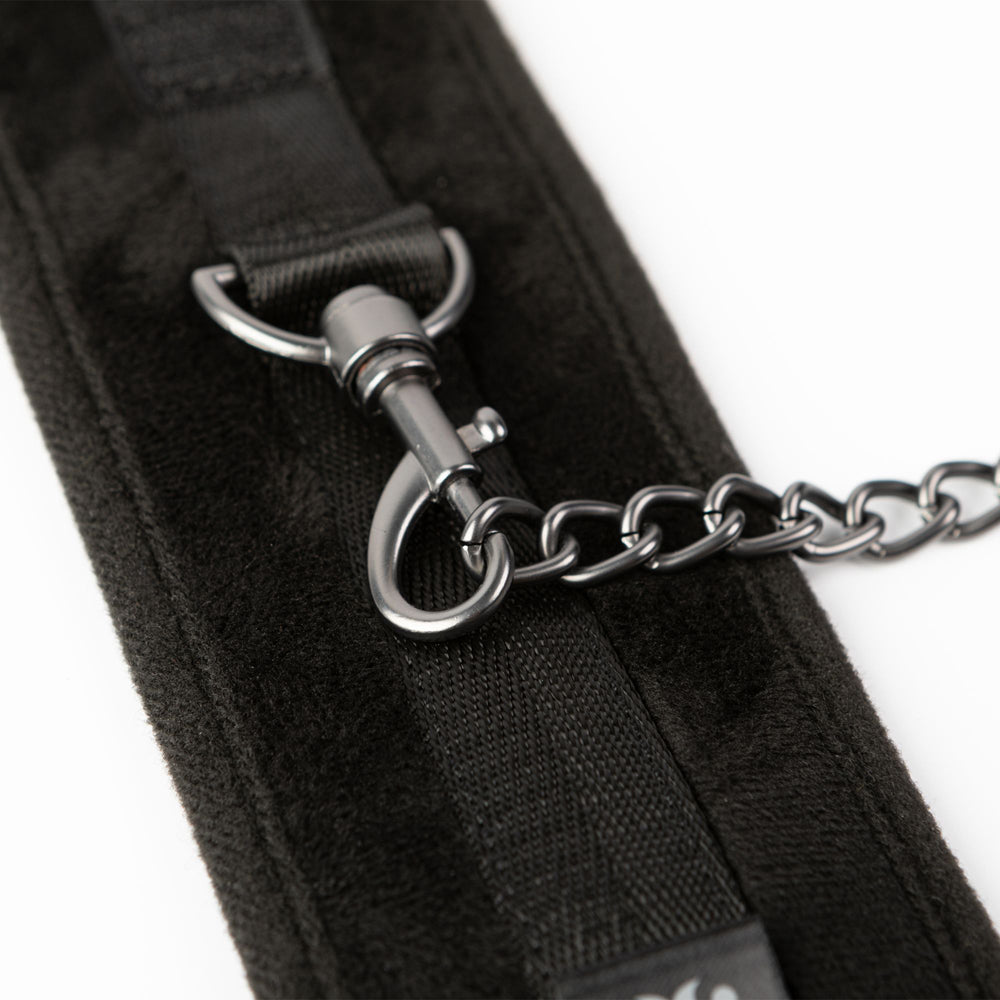 Black padded ankle restraints with a metal clasp and chain.