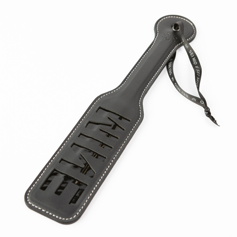 Black faux leather spanking paddle with "MINE" cut out and a ribbon.