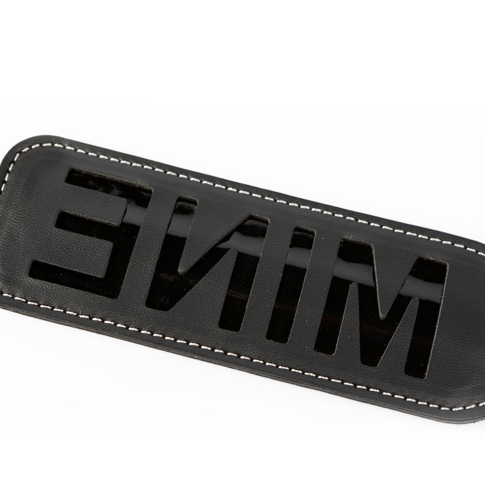 Black faux leather paddle with cut-out "MINE" text.