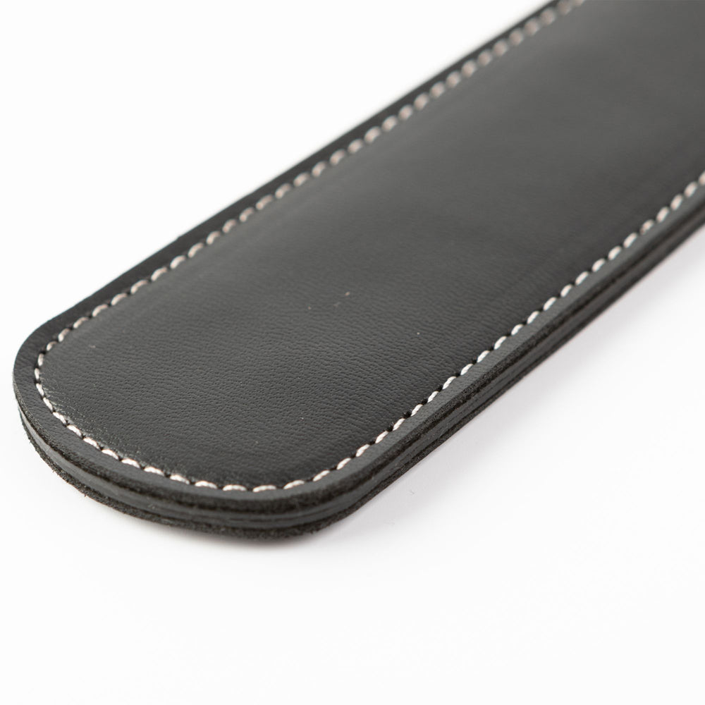 Black faux leather paddle with white stitching.
