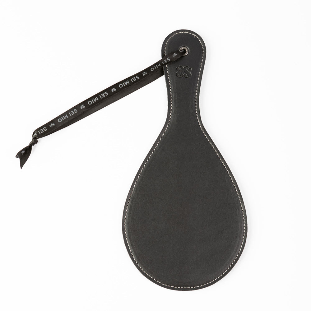 Black faux leather round spanking paddle with a black ribbon and white stitching.