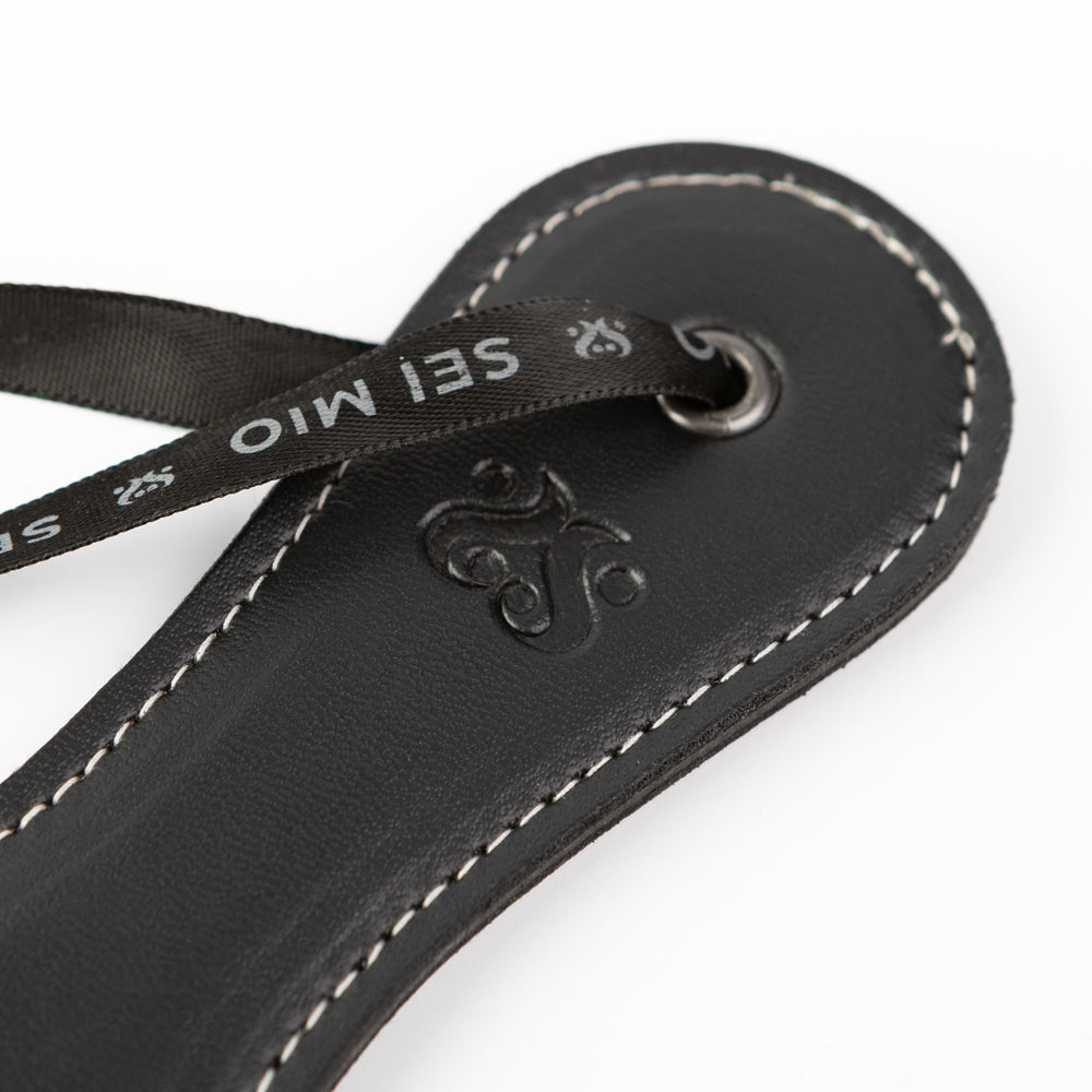 Black faux leather spanking paddle with "Sei Mio" ribbon detail.