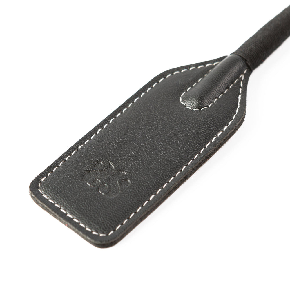 Black leather riding crop with white stitching and a subtle embossed logo.