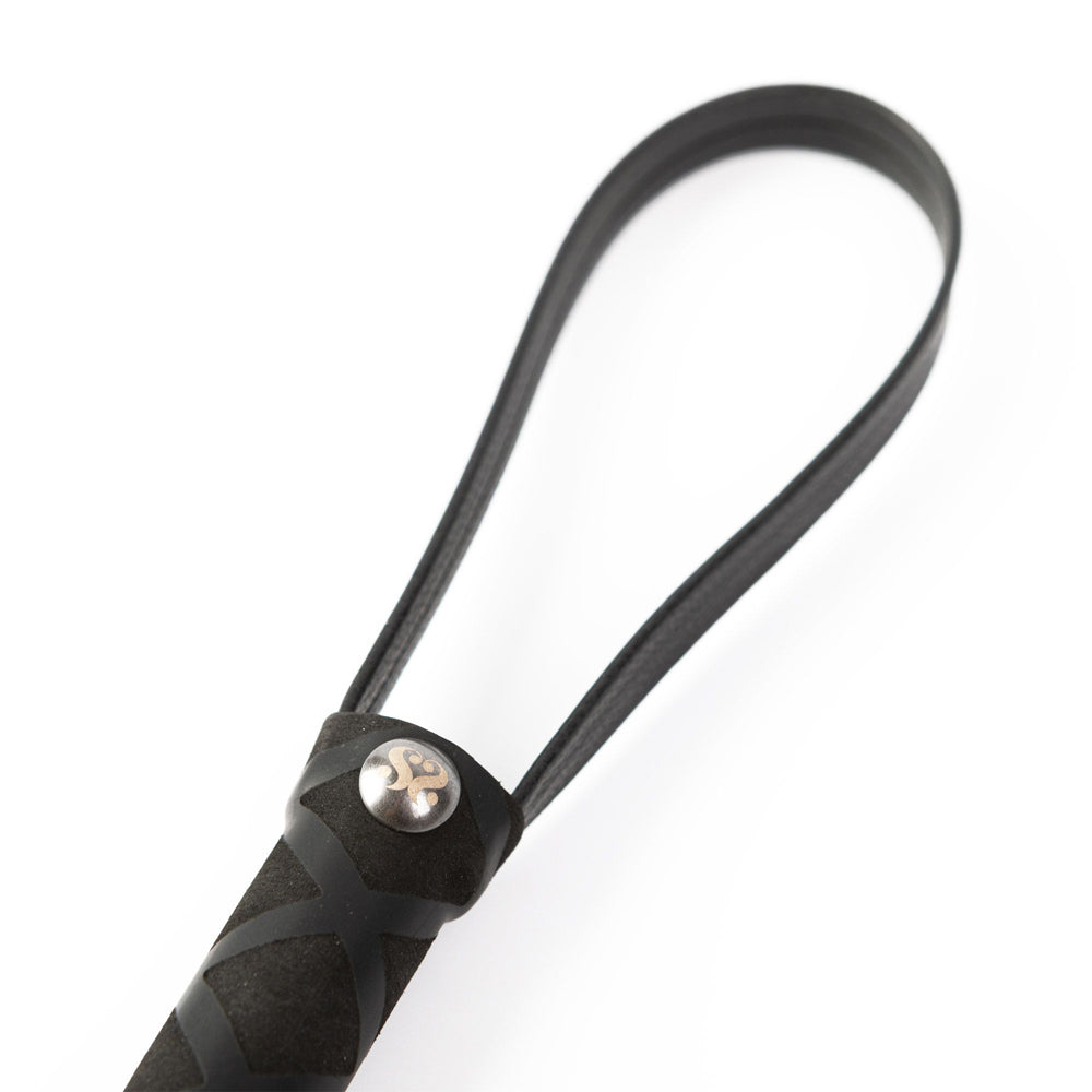 Close-up of a black faux leather flogger with a non-slip handle and wrist loop.