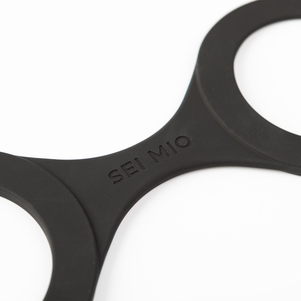 Black silicone hand restraints with "SEI MIO" embossed on them.