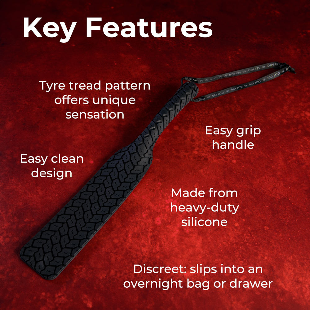 A black silicone spanking paddle with a tire tread texture and easy grip handle.