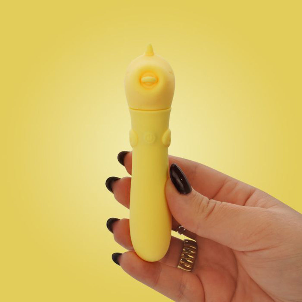 A yellow, chick-shaped vibrator held in a hand with dark nail polish.