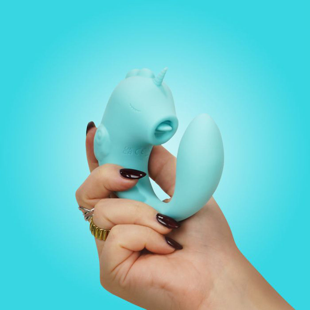 A teal unicorn-shaped dual motor stimulator held in a hand.