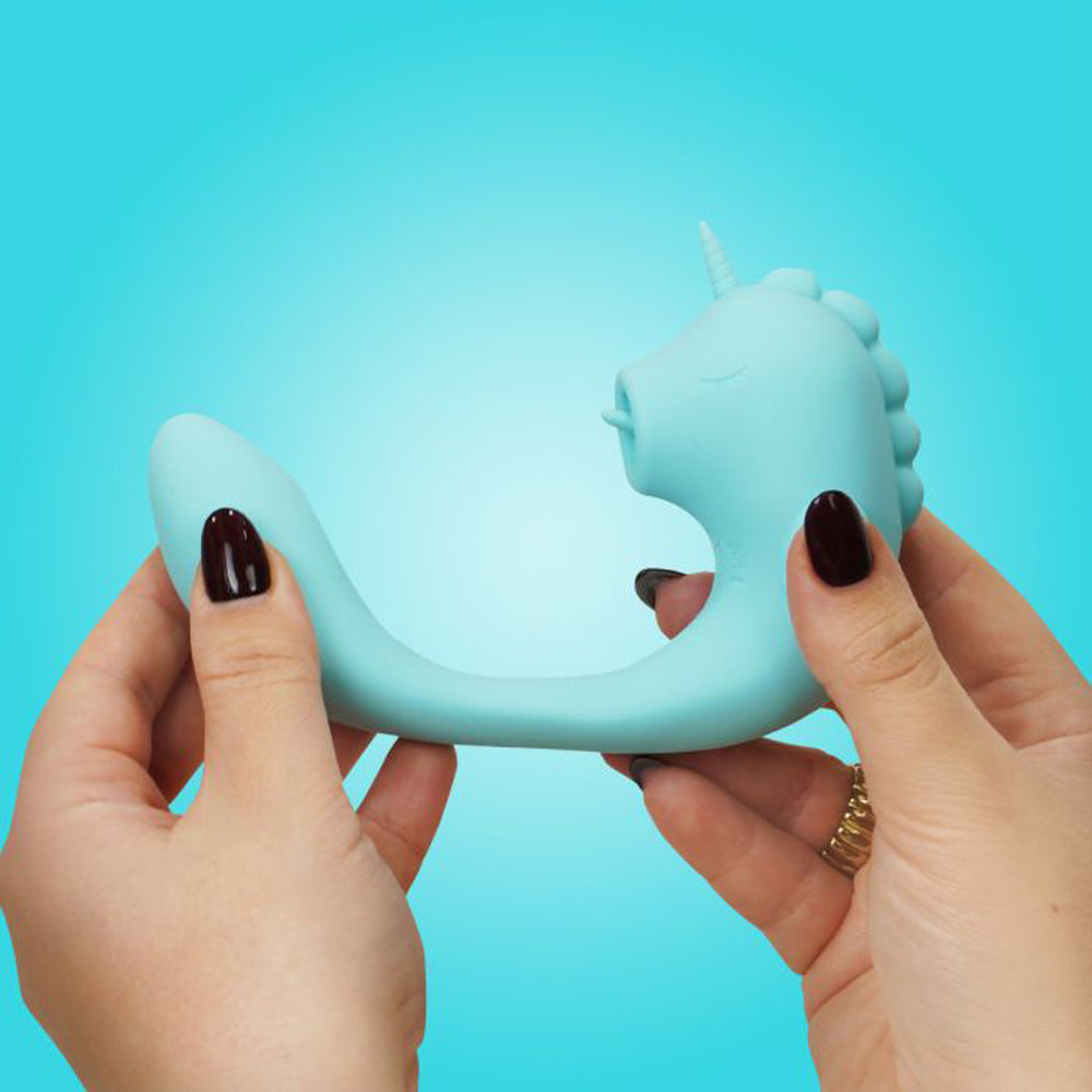 A light blue unicorn-shaped dual motor stimulator held by two hands.