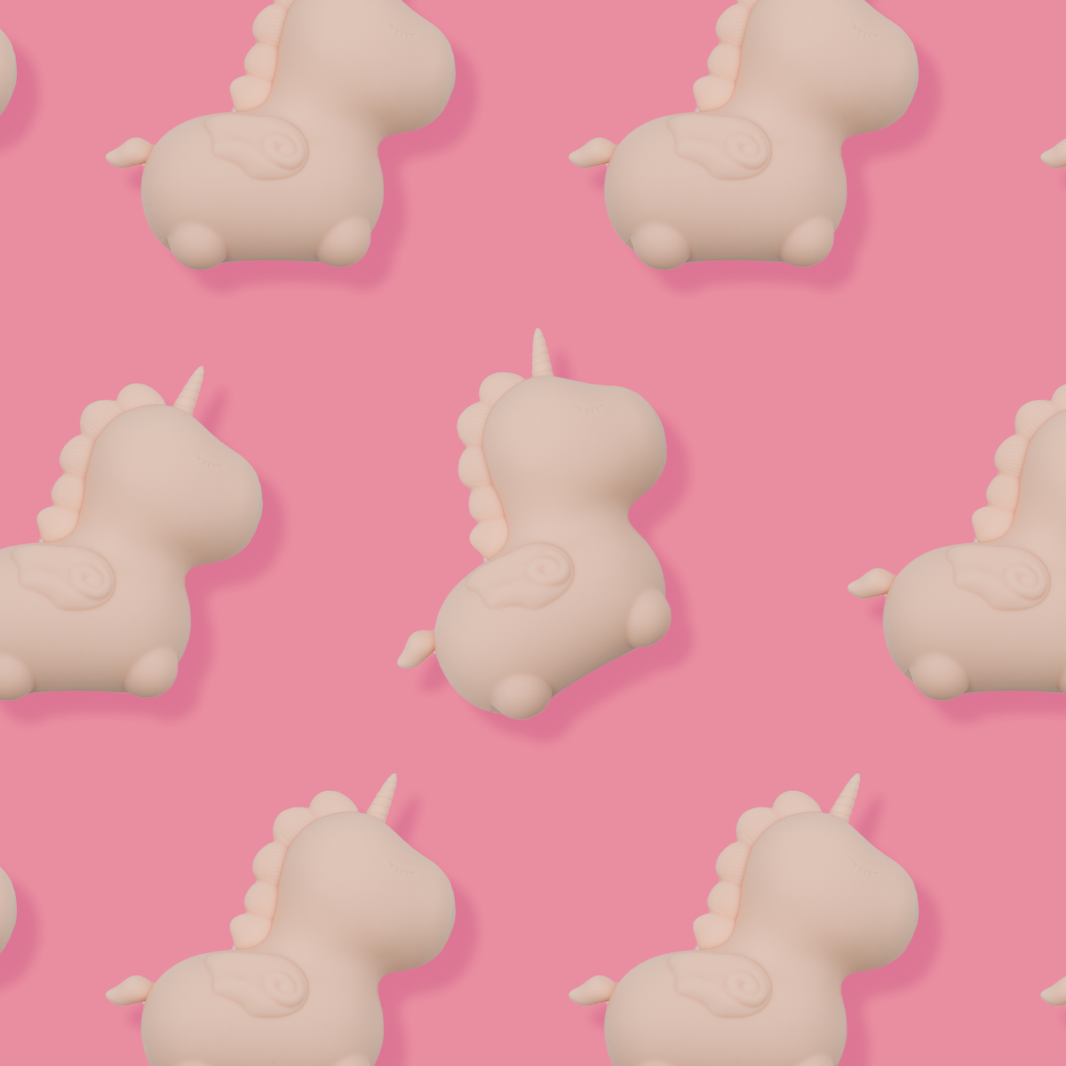A seamless pattern of light pink silicone unicorn toys on a pink background.