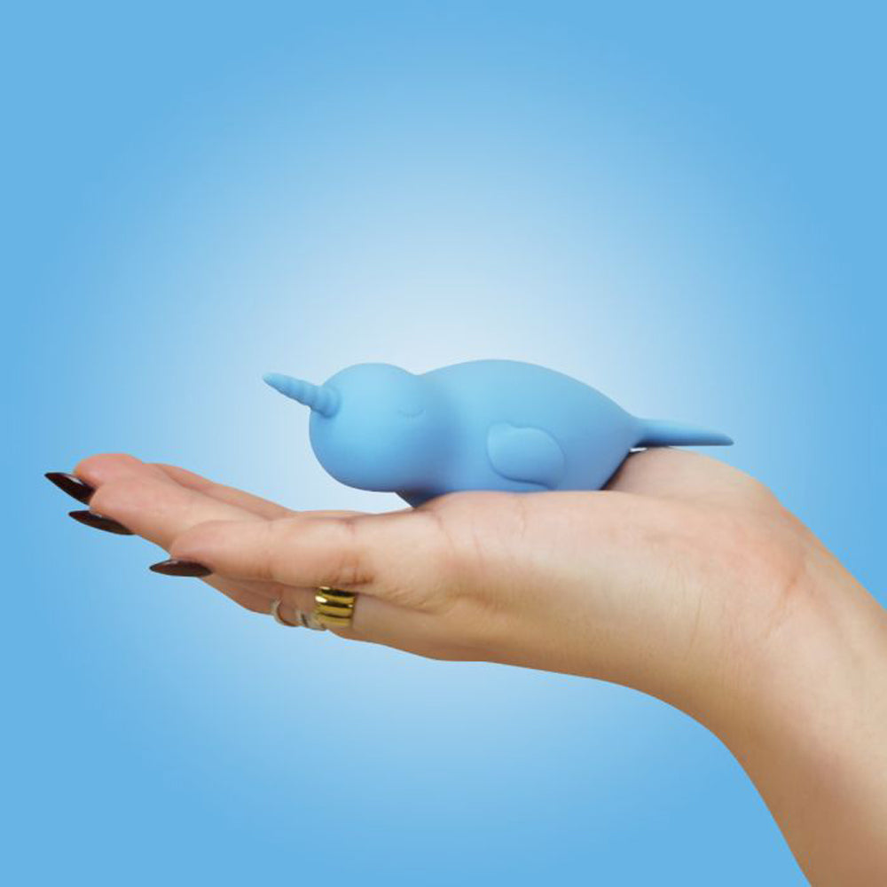 A blue silicone narwhal vibrator rests on a hand.