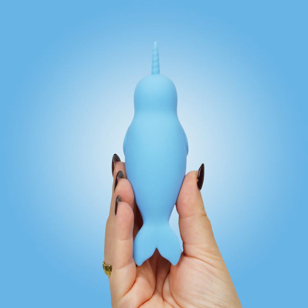 A light blue silicone narwhal vibrator held in a hand.