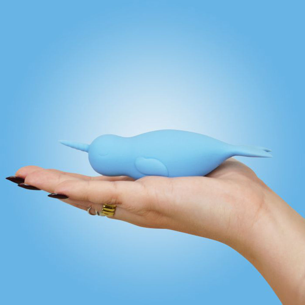 A blue silicone narwhal vibrator rests on a hand.