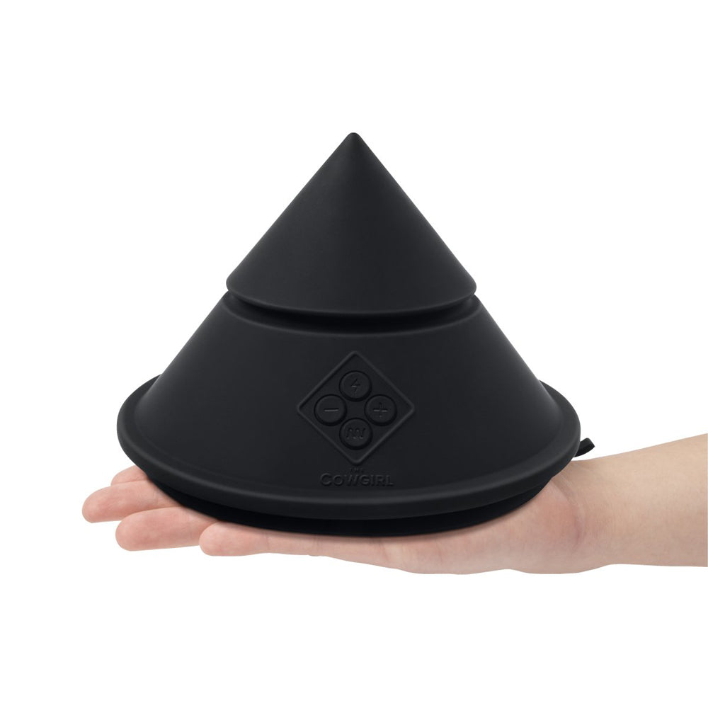 A black, cone-shaped vibrator with control buttons and the word "Cowgirl" on it, held in a hand.