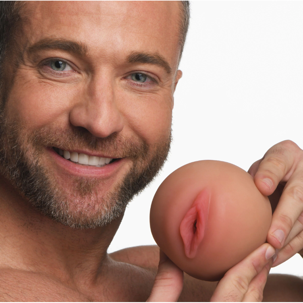 A man smiles holding a realistic dual-texture masturbator stroker.