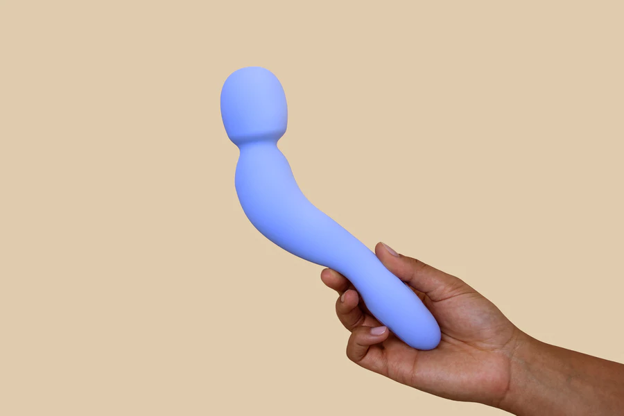 A periwinkle silicone wand vibrator held in a hand.