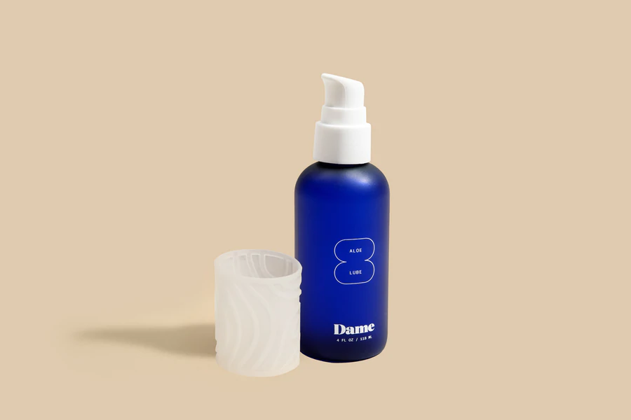 A blue bottle of Dame Aloe Lube with a white pump and a textured white cap.