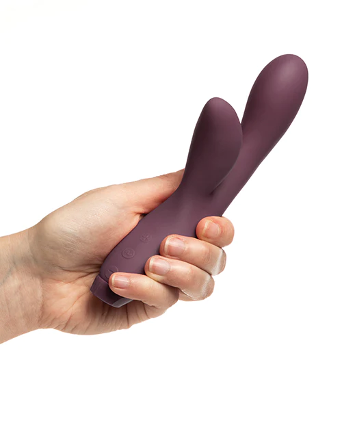 A hand holds a purple rabbit vibrator with two pointed ends.