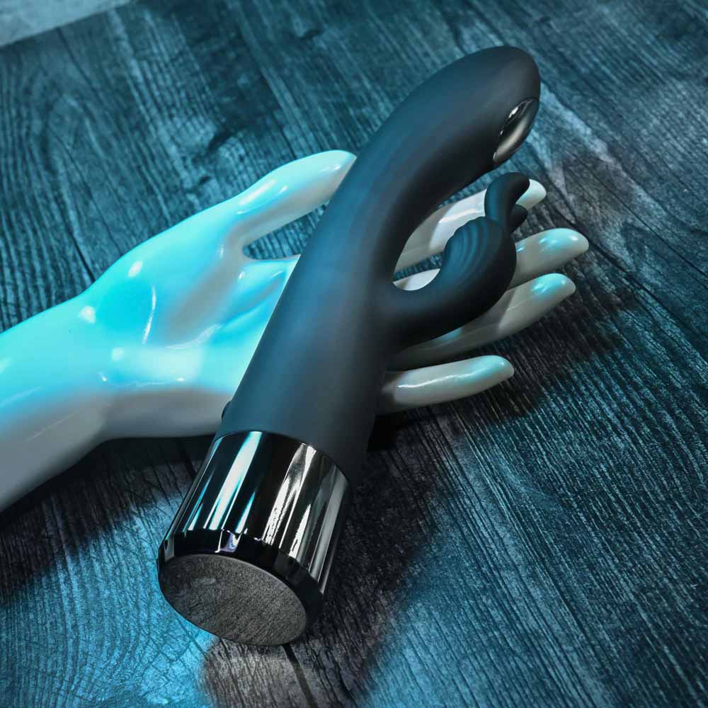 Black G-spot rabbit vibrator with chrome accents on a mannequin hand.