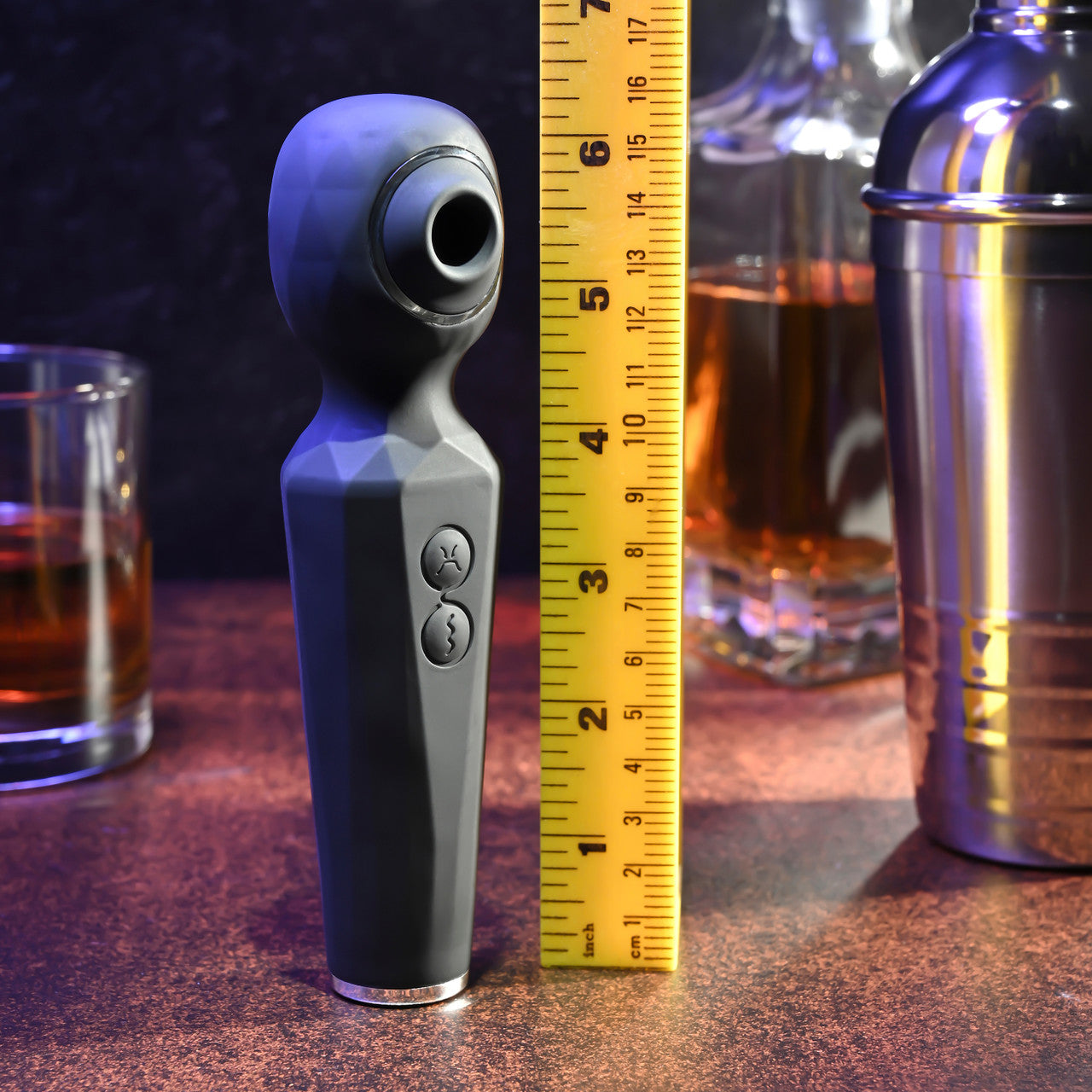 A grey dual motor wand vibrator with a textured head and two buttons, shown next to a ruler.
