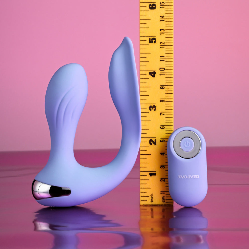A purple dual vibrating remote control wearable with a ruler for scale.