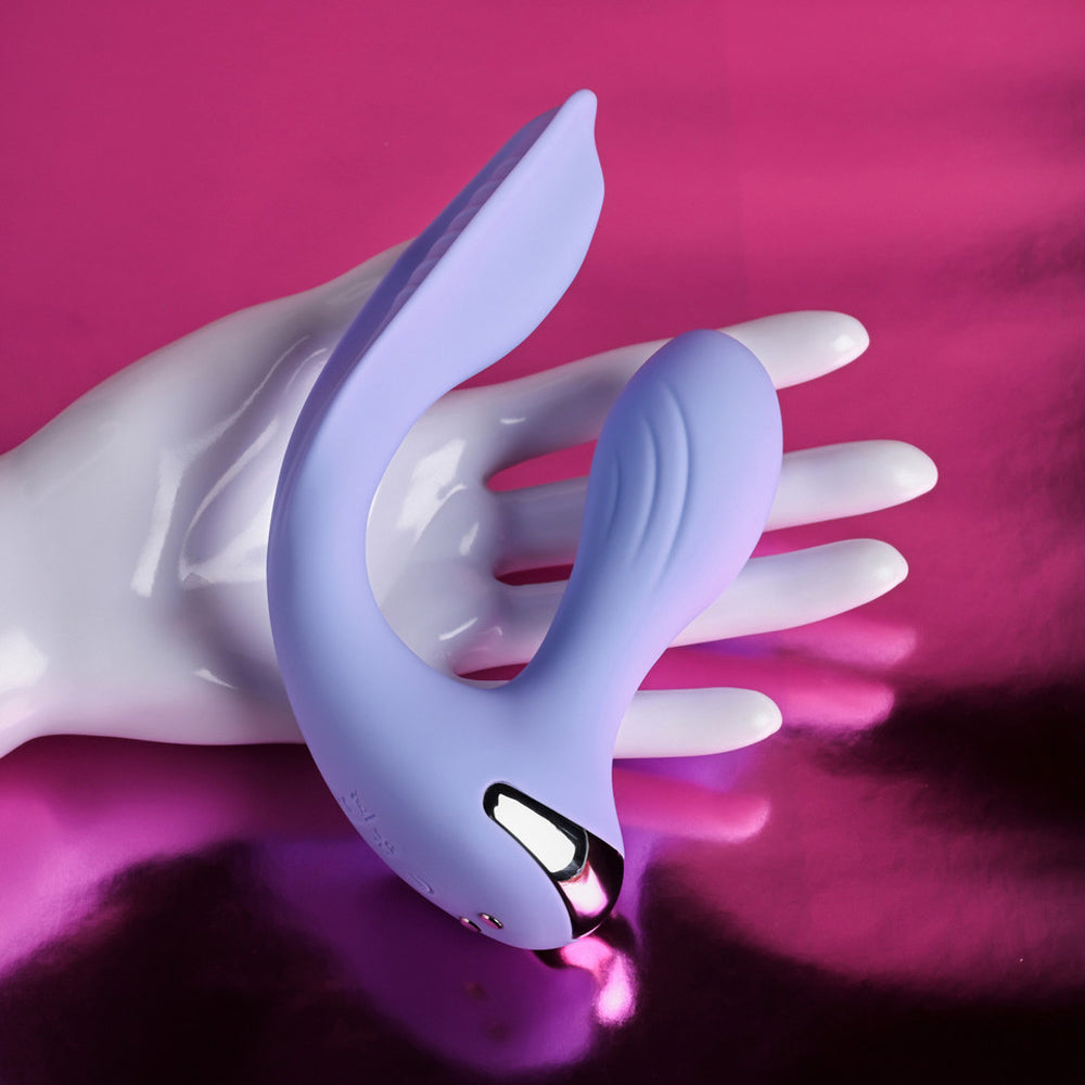 A purple dual vibrating wearable rests on a white mannequin hand.