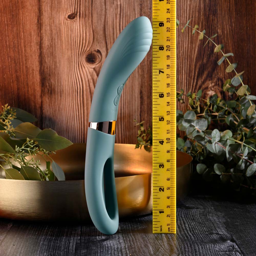Teal silicone vibrator with a curved shaft and flicking end, shown next to a ruler.