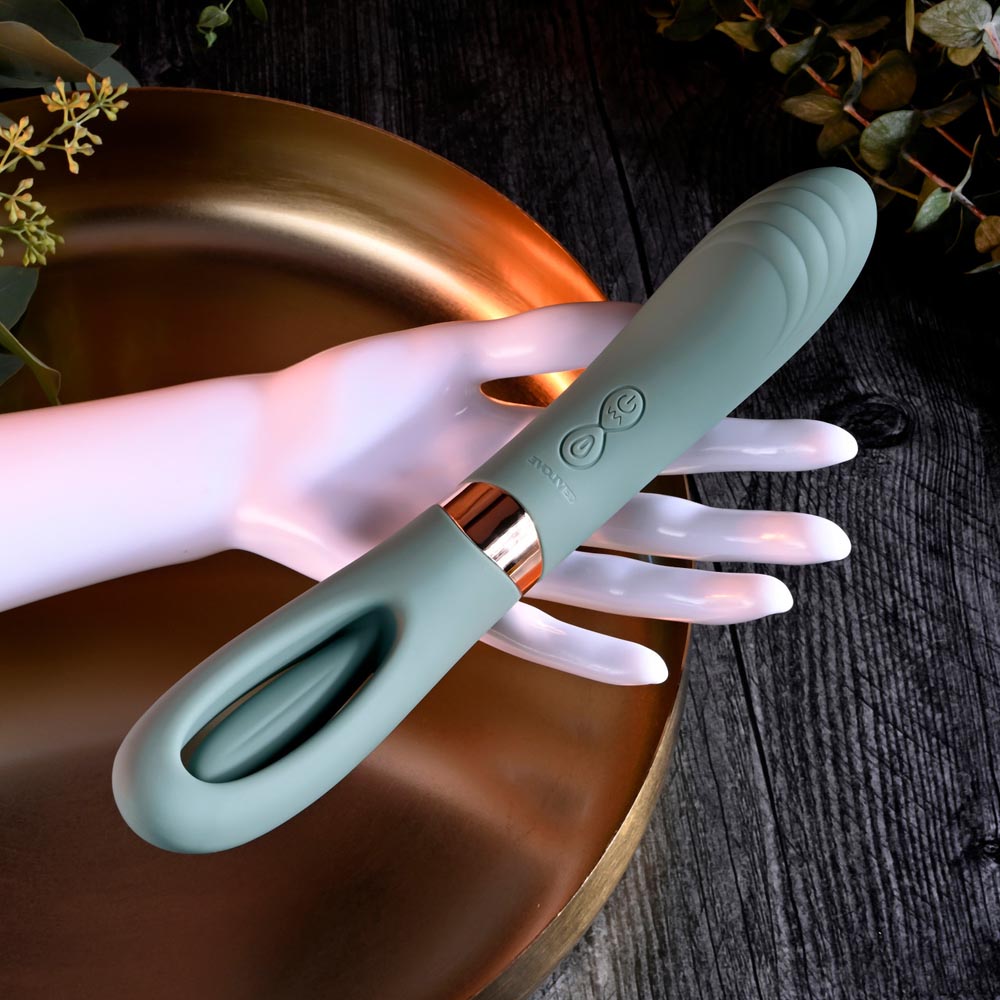 A teal silicone vibrator with a loop handle rests on a mannequin hand.