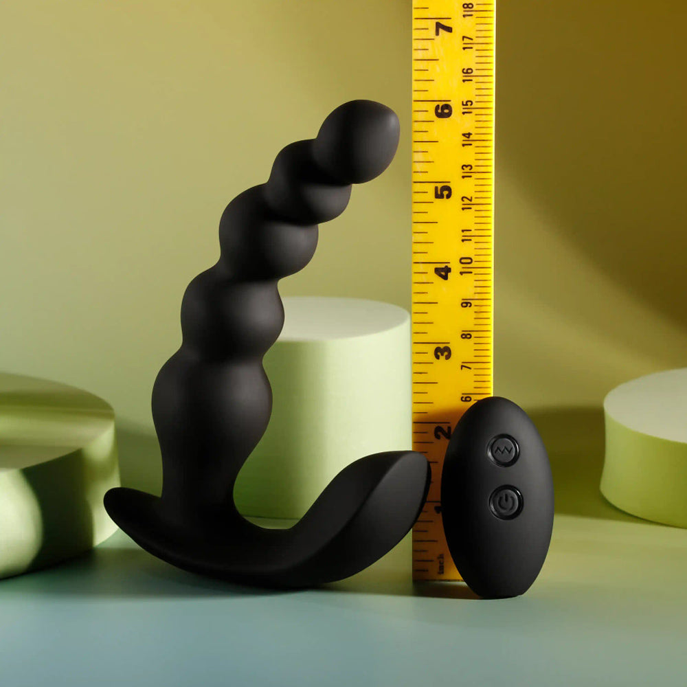 Black beaded vibrator with remote control and ruler for scale.