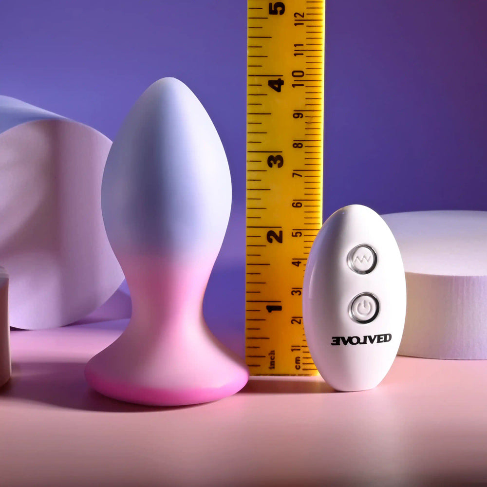 A silicone anal plug with a remote control and a ruler for scale.