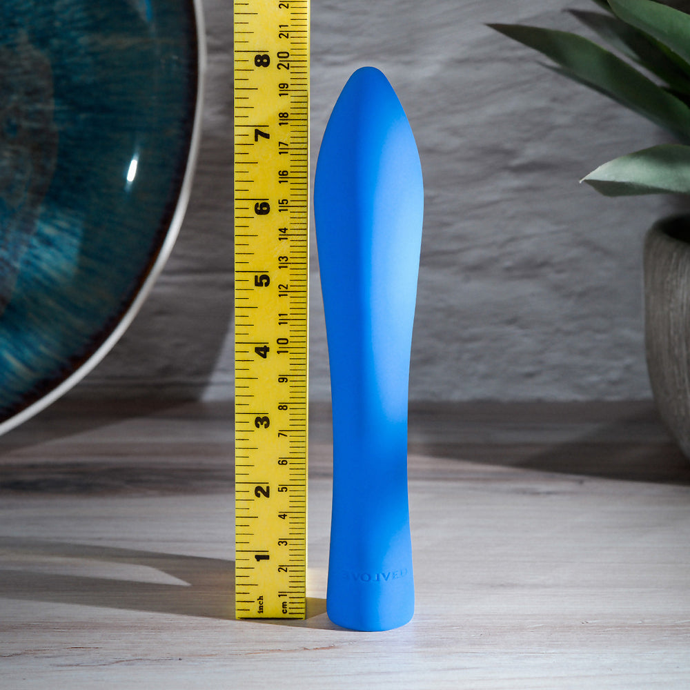 A blue silicone vibrator with a tapered tip is shown next to a ruler.