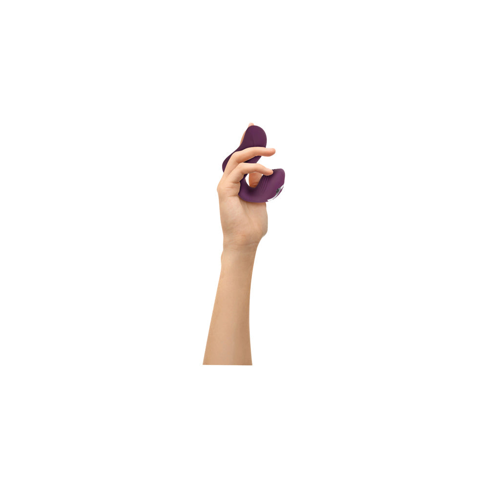 A purple dual motor finger vibrator held in a hand.