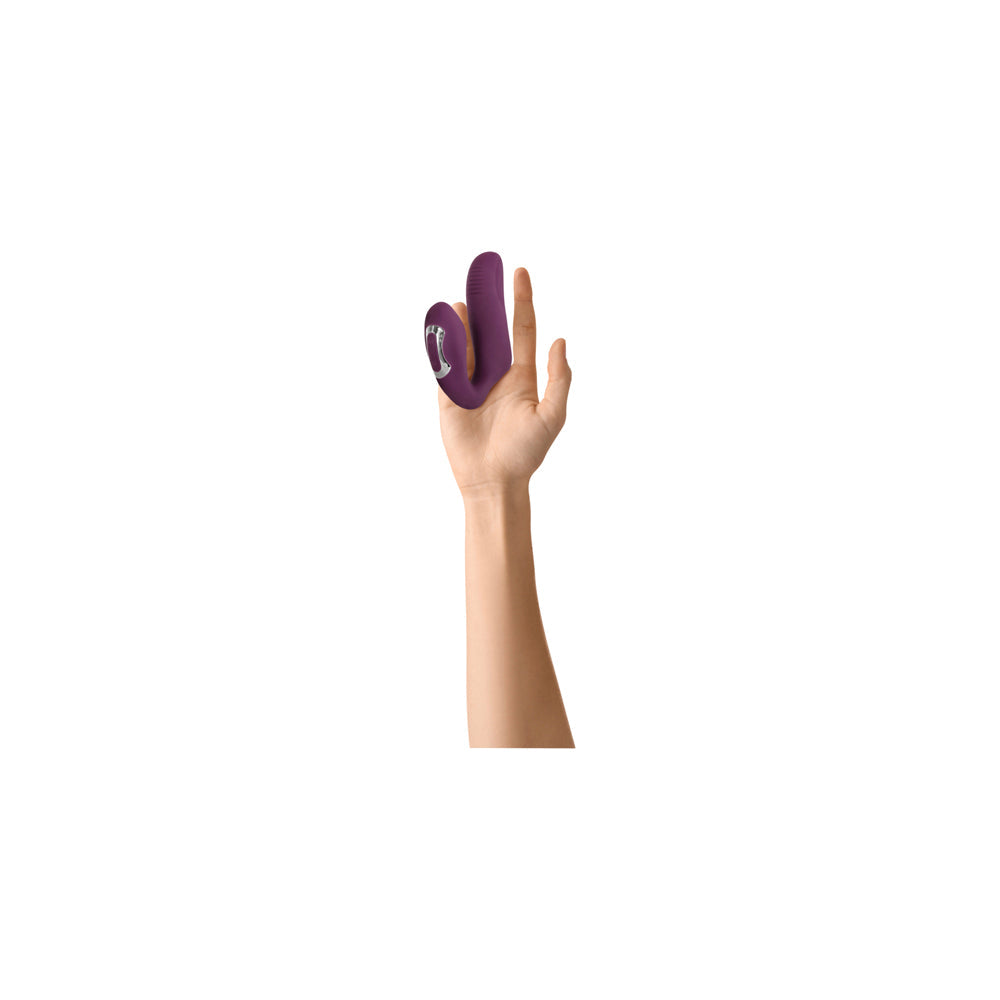 Purple dual motor finger vibrator held on a hand.