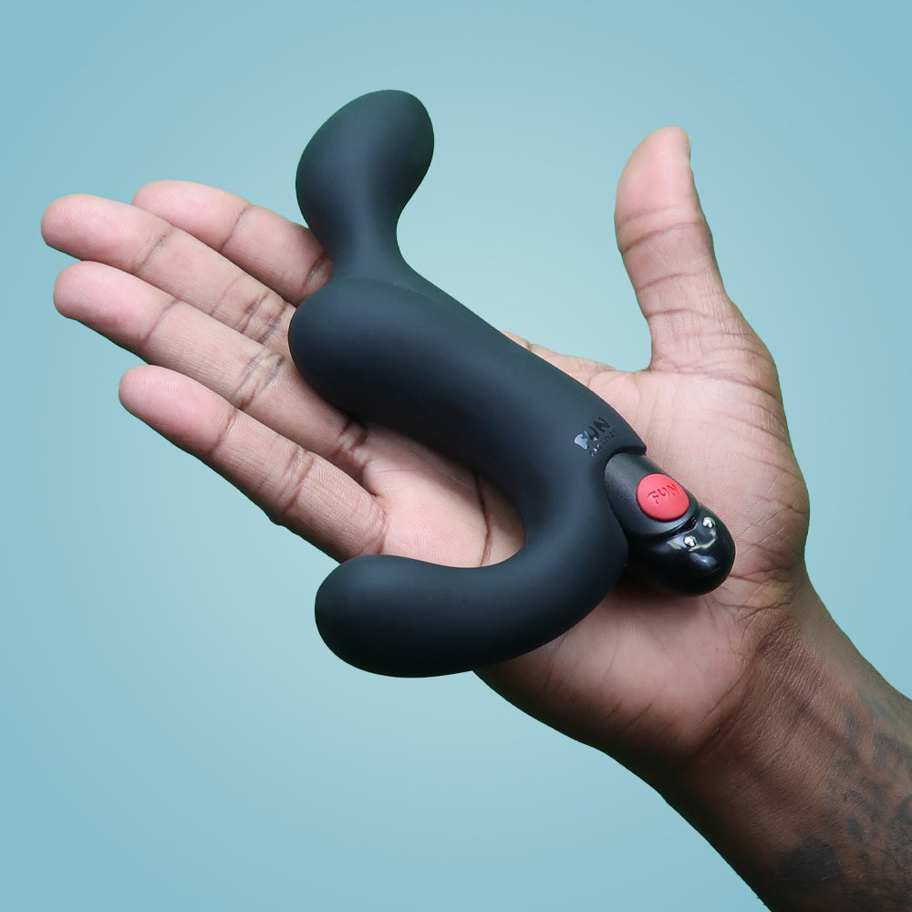 Black vibrating prostate plug held in a hand.