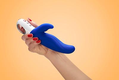 A blue and white dual motor silicone G-spot vibrator held in a hand.