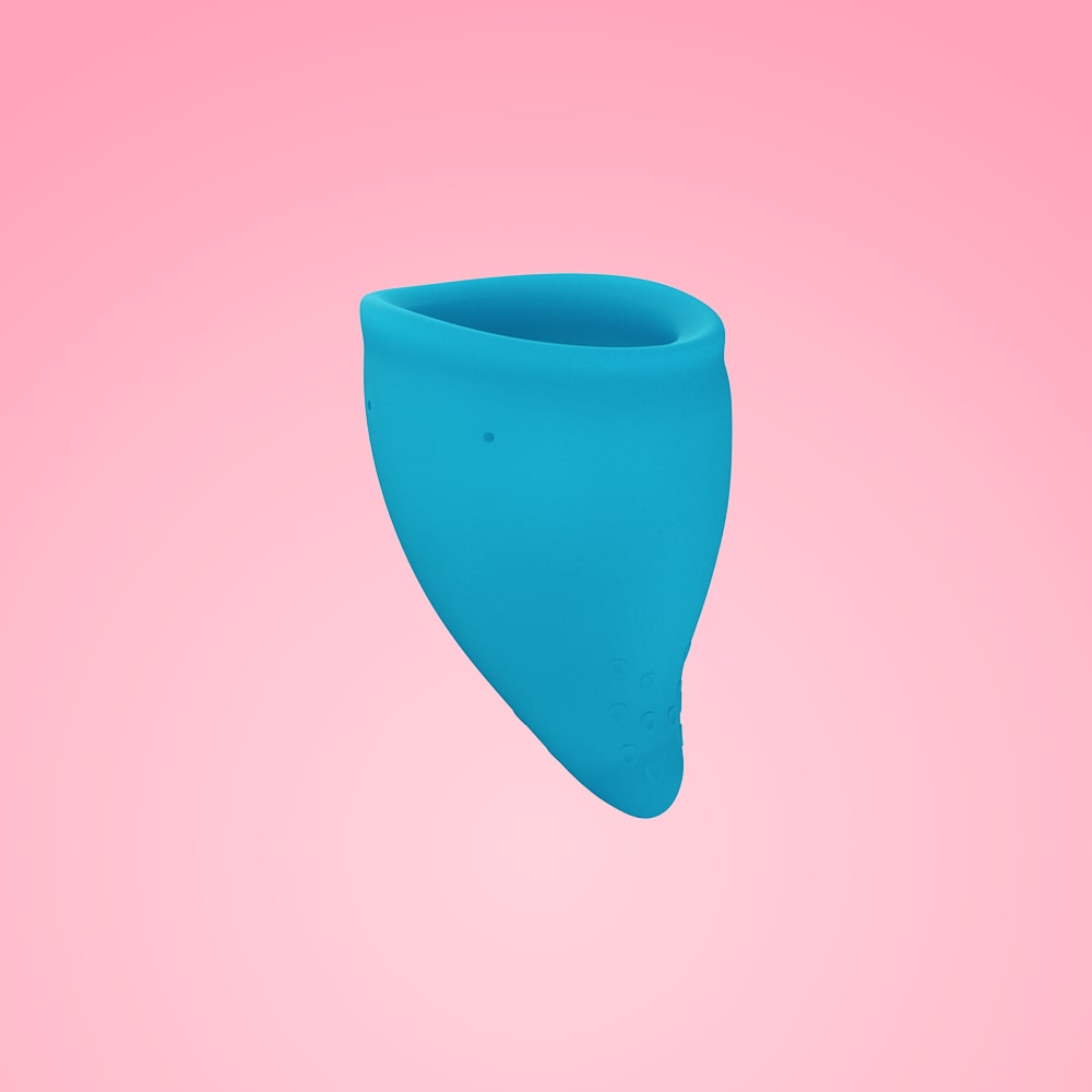 A blue reusable menstrual cup with a textured base against a pink background.