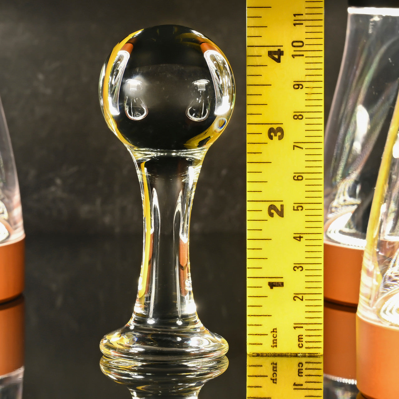 Glass ball anal plug with a ruler showing its size.