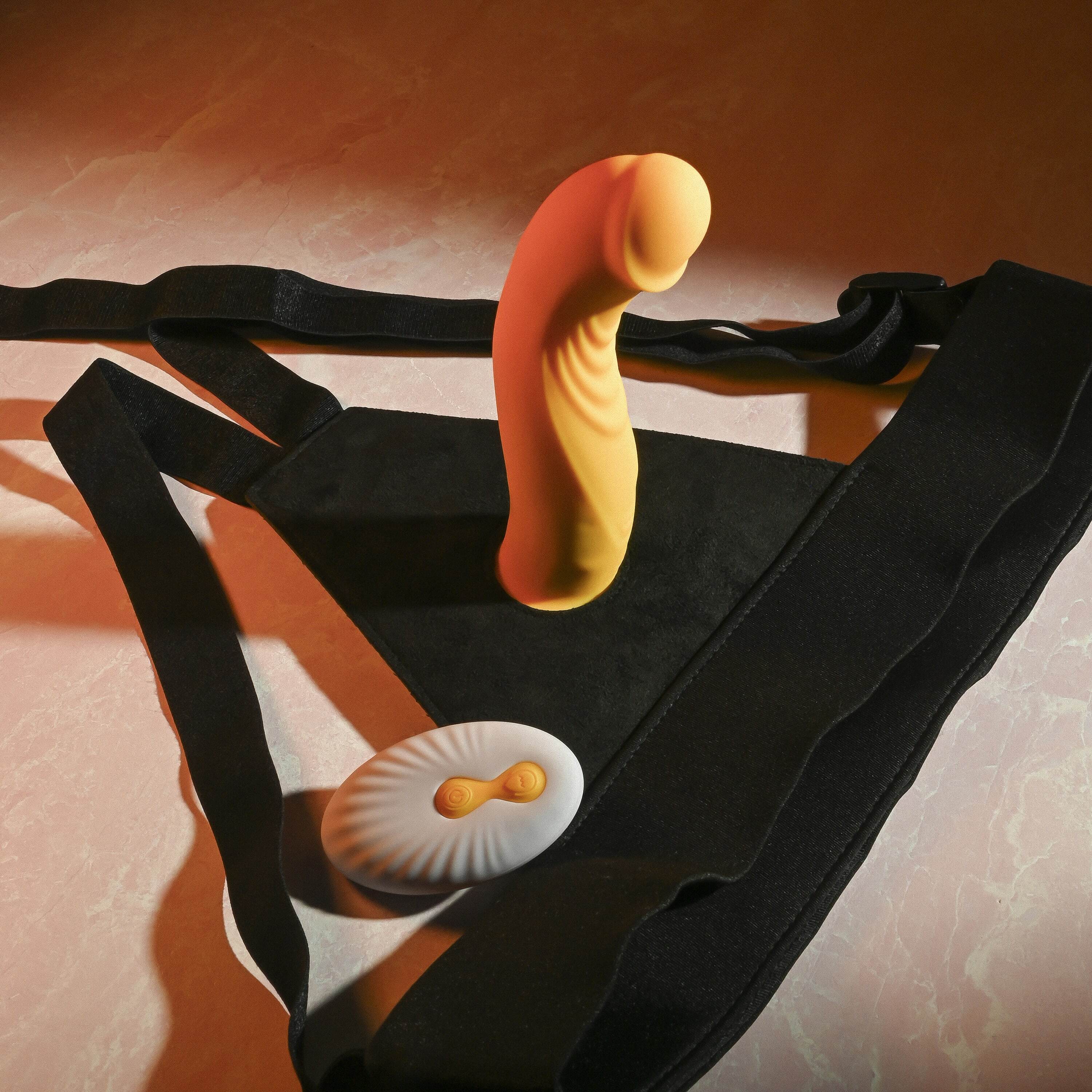 Yellow strap-on dildo with a white remote and black harness.