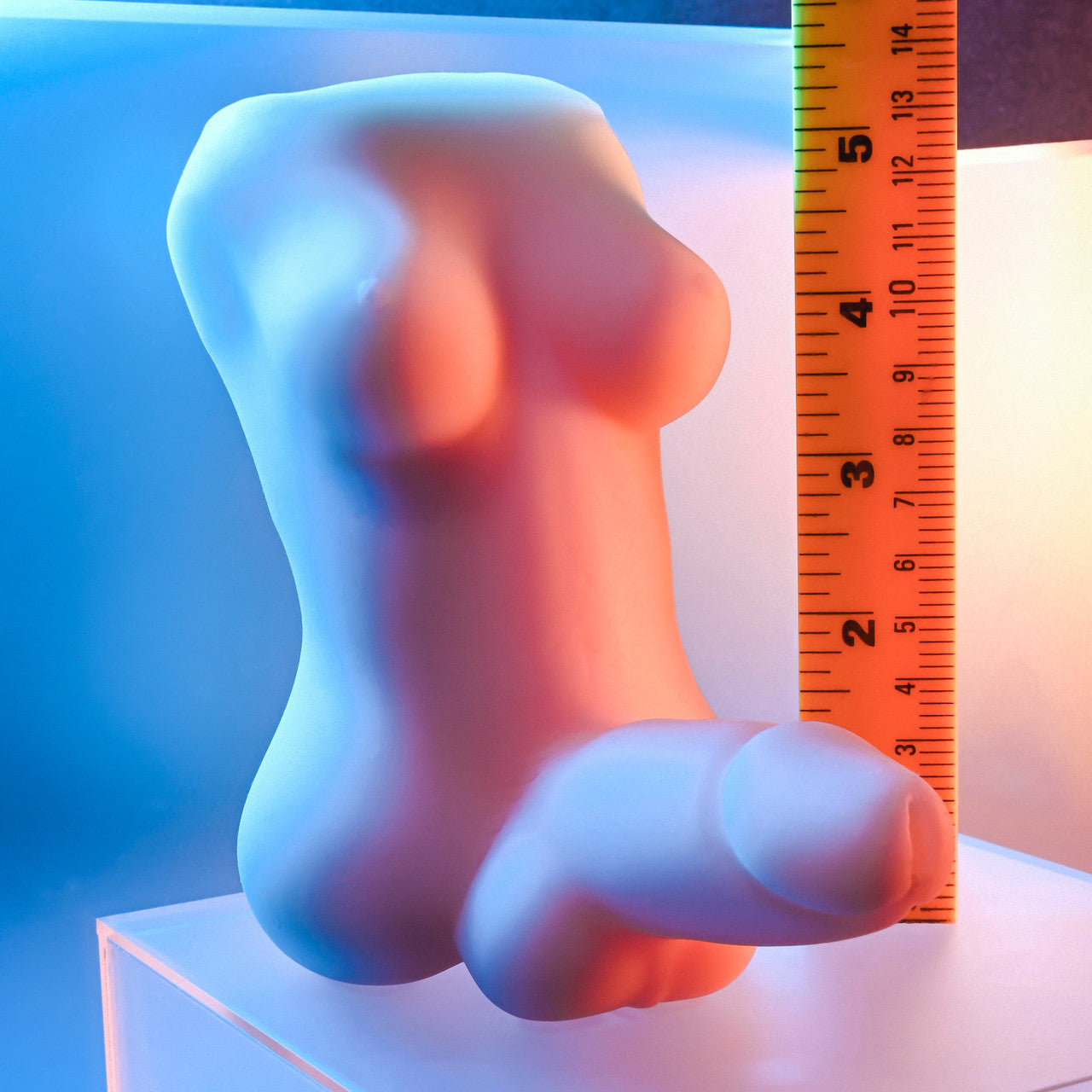 Gender-X textured TPE stroker with integrated C-ring, shown next to a ruler.