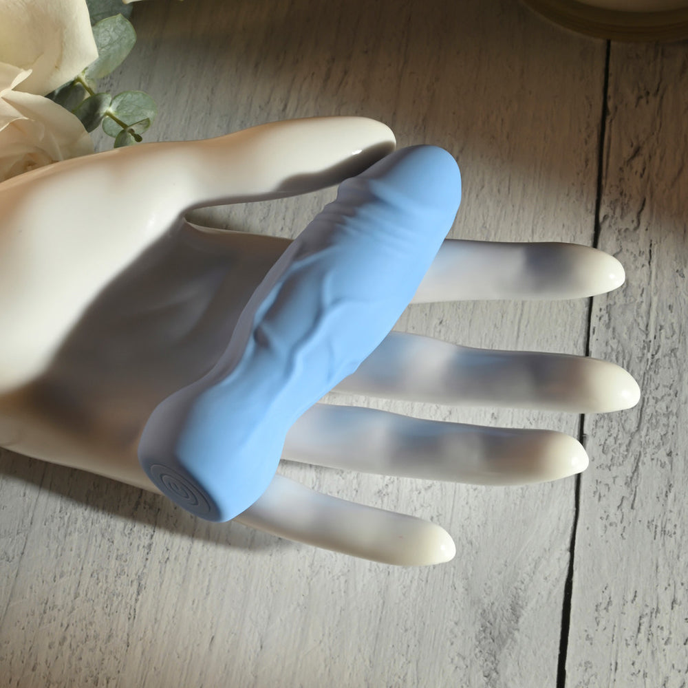 A light blue textured vibrator rests on a white mannequin hand.